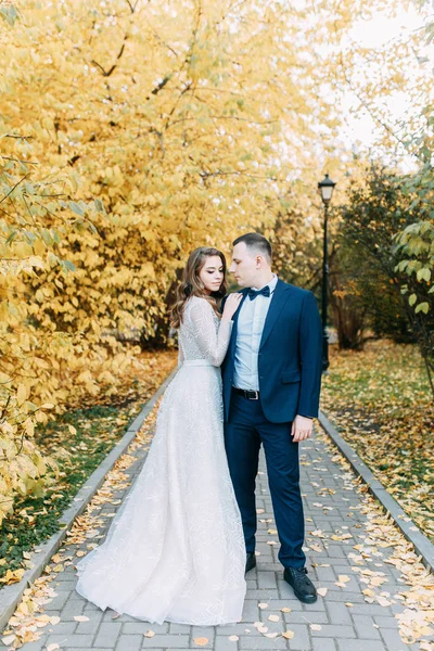 Autumn wedding in European style. Beautiful couple in suit and white dress in Park.