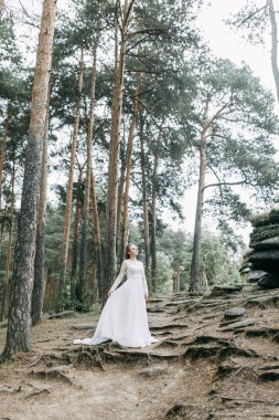 Avrupa tarzında zarif bir tören. Ormanda uçan beyaz elbiseli güzel gelin. 