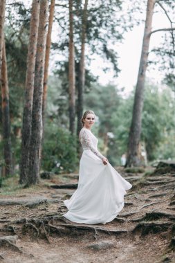 Avrupa tarzında zarif bir tören. Ormanda uçan beyaz elbiseli güzel gelin. 