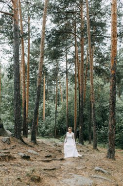 Avrupa tarzında zarif bir tören. Ormanda uçan beyaz elbiseli güzel gelin. 