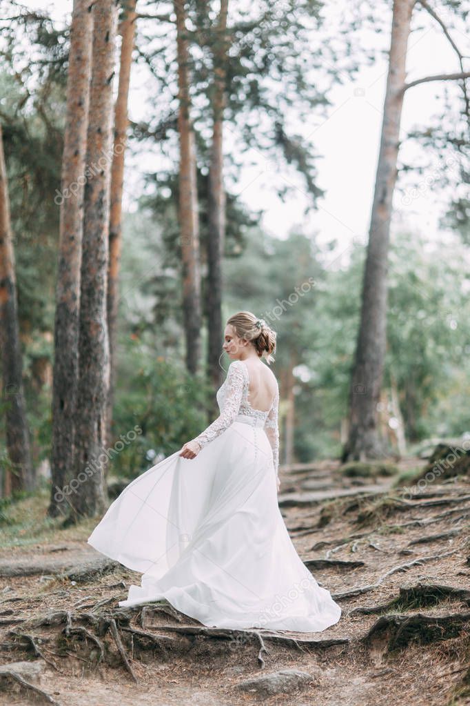 Elegant ceremony in European style. Beautiful bride in white flying dress in the forest. 
