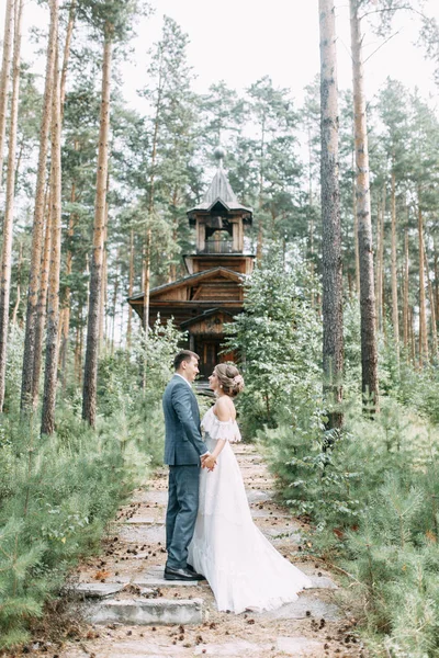 Stylish couple on the background of a wooden temple. Wedding in nature in the woods.