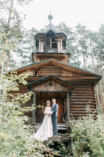 Stylish couple on the background of a wooden temple. Wedding in nature in the woods.