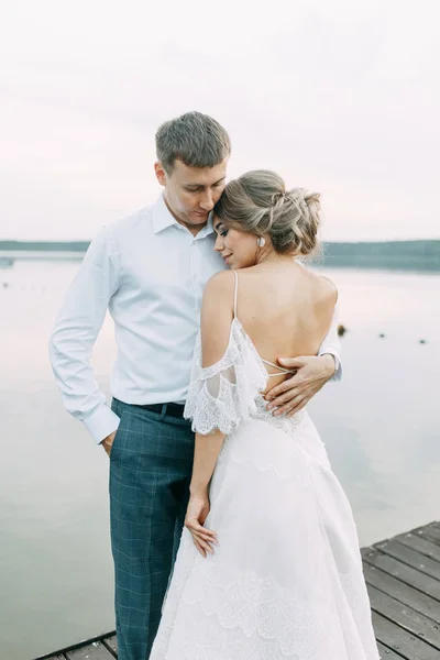 日落时时髦的欧洲婚礼 在湖上的码头上快乐的一对 — 图库照片