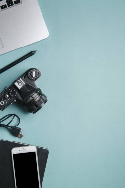 Kameralı, dizüstü bilgisayarı ve telefonu olan düz bir ev. Fotoğrafçının parlak bir arkaplan üzerindeki minimalist düzeni. 
