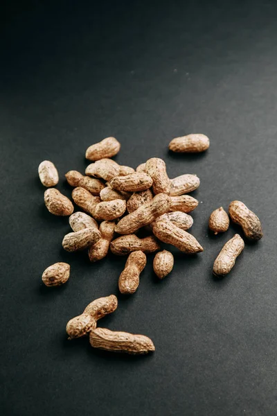 Nuts on a black background. Peanuts in a shell in a slide.