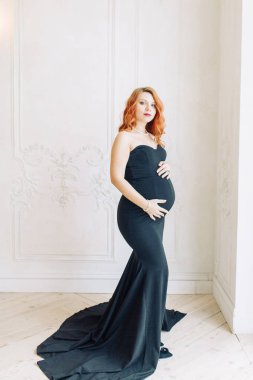 Stüdyoda mutlu bir bebek bekliyor. Siyah elbiseli hamile bir kız.. 