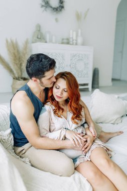 Yatakta kolları bağlı hamile bir kadın. Mutlu çift bebek bekliyor.. 