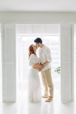 Beyaz elbiseli hamile bir kadın. Mutlu çift tropik bir bebek bekliyor.. 