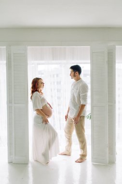 Beyaz elbiseli hamile bir kadın. Mutlu çift tropik bir bebek bekliyor.. 