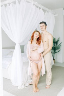 Beyaz elbiseli hamile bir kadın. Mutlu çift tropik bir bebek bekliyor.. 