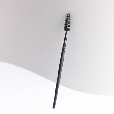 Site için ışıklandırılmış arkaplan. Makyaj sanatçısı için bir alet. Makyaj fırçası. Siyah plastik kaş fırçası. 