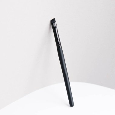 Site için ışıklandırılmış arkaplan. Makyaj sanatçısı için bir alet. Makyaj fırçası. Siyah plastik kaş fırçası. 