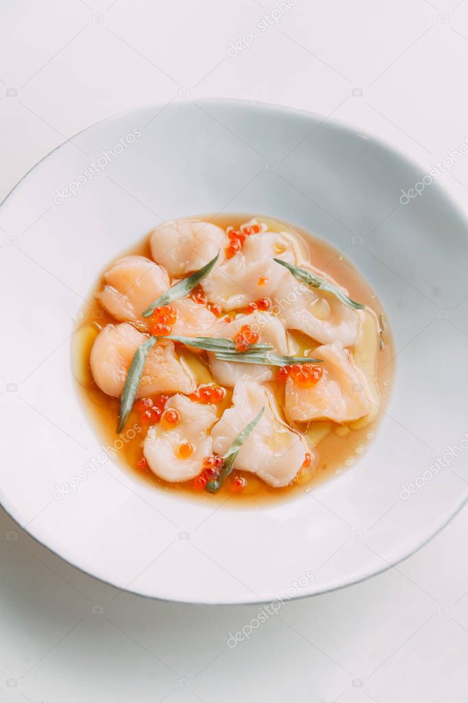  Restaurant seafood dish. Original cuisine. Fresh scallops on a plate. Red caviar in a dish.