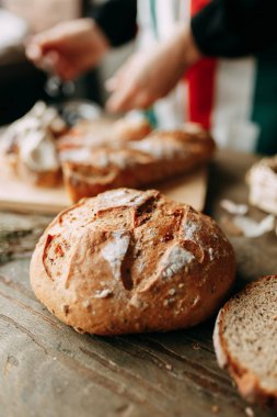  Bir somun beyaz çavdar ekmeği. Taze pişmiş ekmek. Bir kızın elleri ve yemek pişirmesi. Şefin masasında hamur işleri var..
