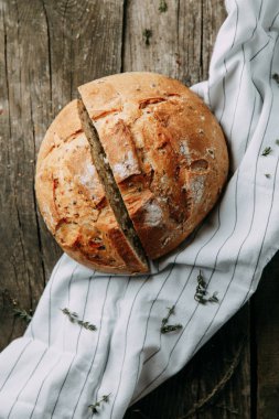 Havluda sarımsak ve yağla pişirmek. Bir somun beyaz çavdar ekmeği. Ahşap zeminde dilimlenmiş ekmek.. 