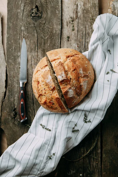 Havluda sarımsak ve yağla pişirmek. Bir somun beyaz çavdar ekmeği. Ahşap zeminde dilimlenmiş ekmek.. 