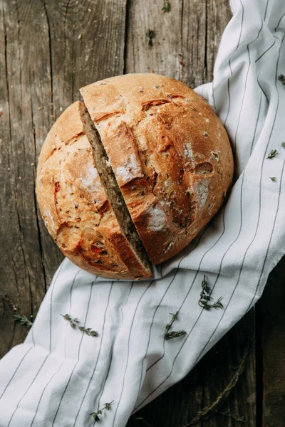 Havluda sarımsak ve yağla pişirmek. Bir somun beyaz çavdar ekmeği. Ahşap zeminde dilimlenmiş ekmek.. 