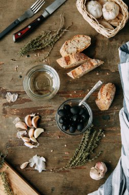 Ahşap zemin üzerinde dilimlenmiş ekmek ve sarımsak. Bir kase yağda zeytin. Flatley 'nin İtalyan yemekleri.. 