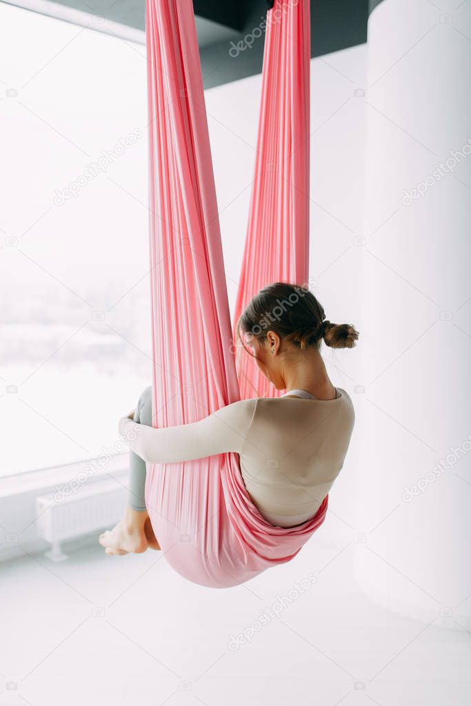 Exercises in the gym. Suspended in the air. Girl in a yoga hammock. Relax and grouped pose. 
