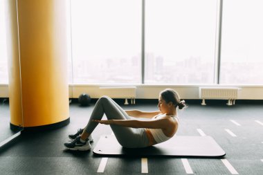 Stretching on a black surface. Press training on the Mat. Girl doing exercises in the gym. 