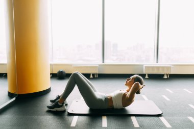 Stretching on a black surface. Press training on the Mat. Girl doing exercises in the gym. 