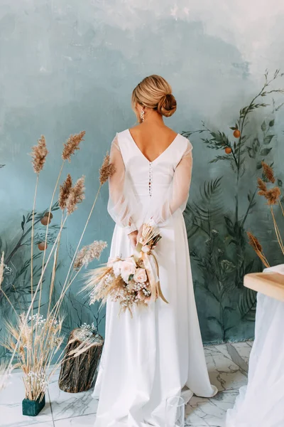 Decor of dried flowers at the ceremony in the European style.Portrait of a beautiful young bride in a wedding dress.