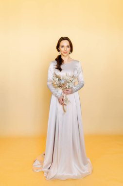 Gelinlikli kız. Düğün çekiminde minimalizm. Stüdyoda sarı arka planda güzel bir gelin.. 