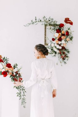 Güllerin kırmızı düğün dekoru. Gelinin portresi güzel sanatlar tarzında. Gelinin kar beyazı stüdyosundaki sabahı. 