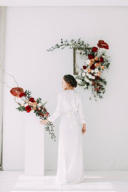 Güllerin kırmızı düğün dekoru. Gelinin portresi güzel sanatlar tarzında. Gelinin kar beyazı stüdyosundaki sabahı. 