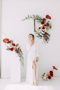 Güllerin kırmızı düğün dekoru. Gelinin portresi güzel sanatlar tarzında. Gelinin kar beyazı stüdyosundaki sabahı. 