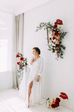 Güllerin kırmızı düğün dekoru. Gelinin portresi güzel sanatlar tarzında. Gelinin kar beyazı stüdyosundaki sabahı. 