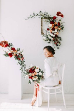 Güllerin kırmızı düğün dekoru. Gelinin portresi güzel sanatlar tarzında. Gelinin kar beyazı stüdyosundaki sabahı. 