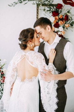  Güzel bir çift ve dantelli elbise. Kırmızı güllerin kemerinin güzel sanatlarla süslenmesi. Avrupa tarzında düğün töreni.