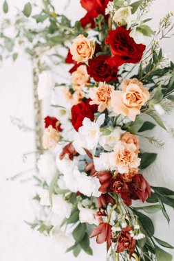Şık bir düğün töreni süsü. Kemerin süslemesi kırmızı güller ve düğün çiçekçisi. Düğün buketlerindeki modern trendler. 