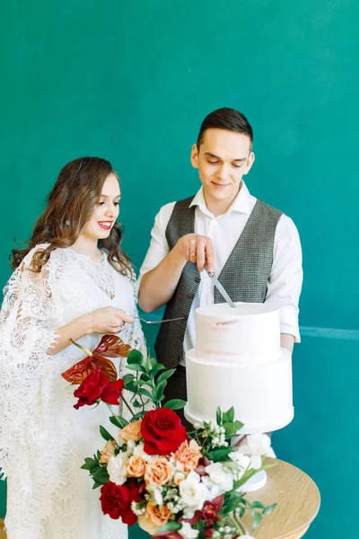 多层蛋糕 上面装饰着红玫瑰 一对新婚夫妇正在切生日蛋糕 — 图库照片