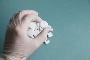 Mavi arka plandaki beyaz tabletler izole edilmiş. Düz tabletlerin yerleşimi. Eldivenli ve haplı. Virüs koruması ve 2019-ncov. 