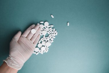Mavi arka plandaki beyaz tabletler izole edilmiş. Düz tabletlerin yerleşimi. Eldivenli ve haplı. Virüs koruması ve 2019-ncov. 