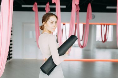  Stretching in the white room by the window. Beautiful girl athlete on the Mat. Flexibility exercises on a light background.