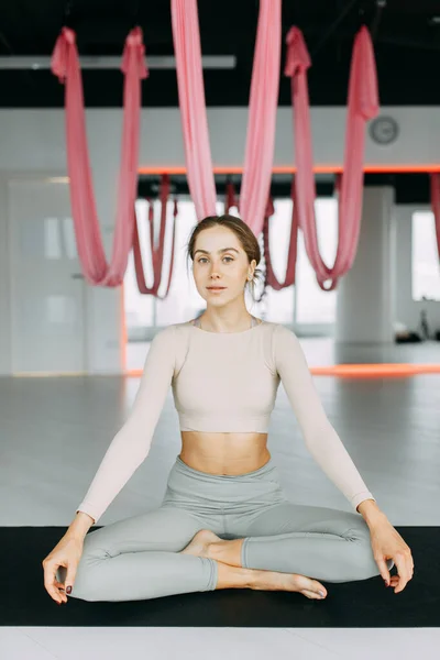 Exercises for self-control in yoga. Bright gym. Relaxed posture during meditation. The girl is sitting on the Mat, relax.