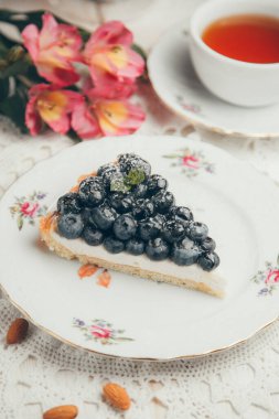  Böğürtlen ve kremalı kek dilimi. Beyaz tabakta bir parça yaban mersinli kek.