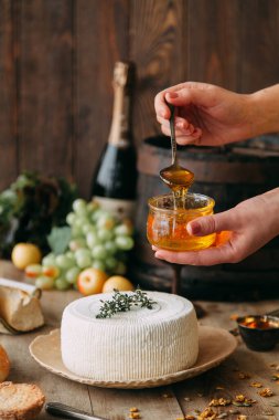  Tabakta büyük, yuvarlak bir peynir. Peynir balla sulanır. Şefin elleri peyniri hazırlar..