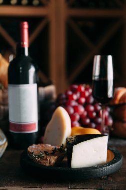 Bir dilim sert parmesan peyniri ve bir şişe şarap. Peynirli, şaraplı ve ekmekli kompozisyon. 