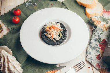 Restoranda soslu pilav servis ediliyor. Siyah pilav pilavı. Beyaz tabakta karidesli risotto. 