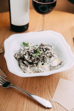 Restoranda soslu pilav servis ediliyor. Siyah pilav pilavı. Beyaz tabakta karidesli risotto. 