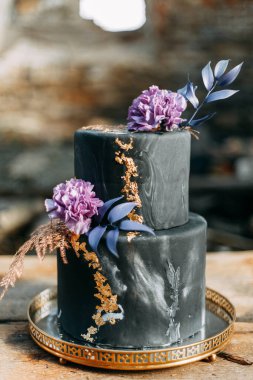 Koyu renkli, çiçekli, çok katlı bir pasta. Düğün pastası. Düğün töreninde doğum günü pastası. 