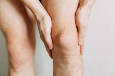  Eklem yaralanmaları, iş yerinde yorgunluk. Yaralanma alanı, temiz bir arkaplanda görüntü. Adamın dizinde spazm.