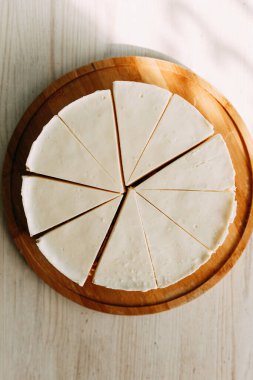  Pasta kısa hamur parçalarına bölünmüş. Tahtada kremalı cheesecake.