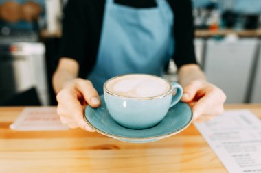 Uzattı ve bana bir fincan tabağında verdi. Kahveni kafeye götür. Kahve fincanı Barista 'nın elinde.. 