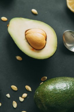 Tohumları olan karanlık bir arka planda avokado. Doğal vejetaryen yemekleri. Olgun avokado kesimi. 